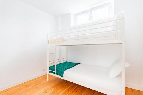 a white bunk bed in a room with a wooden floor at Oeiras Spacious and Coastal Flat in Paço de Arcos