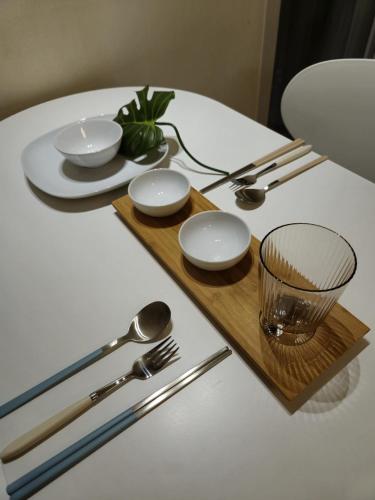 a white table with a wooden tray with plates and silverware at Mango&Haru House in Seoul