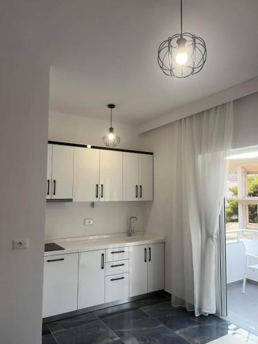 a white kitchen with white cabinets and a window at Nōya Suites SR in Sarandë