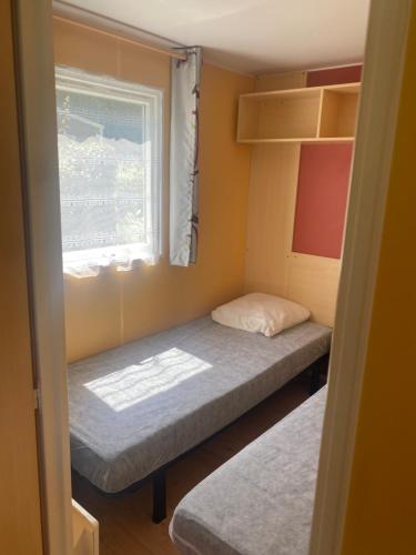 een kleine kamer met twee bedden en een raam bij Camping Chantecler in Luchon