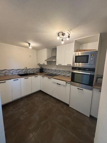une cuisine avec des armoires blanches et un micro-ondes dans l'établissement Maison de ville, à Listrac-Médoc
