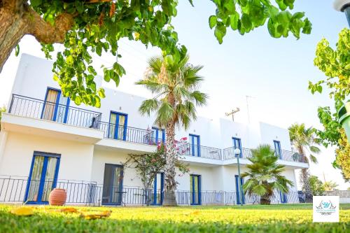 a white building with blue windows and palm trees at Royal Club Hotel - Aqua Poolside Bliss in Kamenitsotaíika