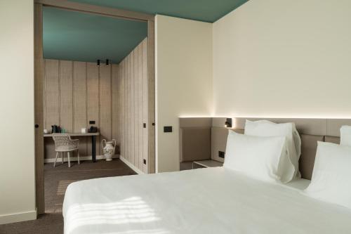 a bedroom with a large white bed and a desk at WANDERLUST HOTEL - SUITE & SPA - APARTMENTS & VILLAS - Bardolino, Lago di Garda - Verona in Bardolino