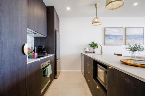 a kitchen with wooden cabinets and a counter top at Elegant Bay Side 1-Bed Apartment with Views in Batemans Bay