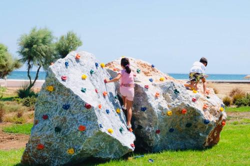 two people are climbing on a rock wall at Thalassa Beach Resort in Vokolidha