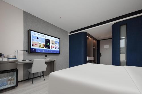 a bedroom with a bed and a tv on a wall at Atour Light Hotel Dongguan Songshan Lake University Town in Dongguan
