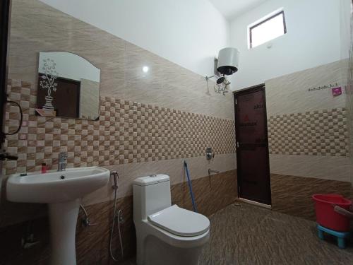 a bathroom with a sink and a toilet and a mirror at Hotel Mehra Inn in Haldwāni