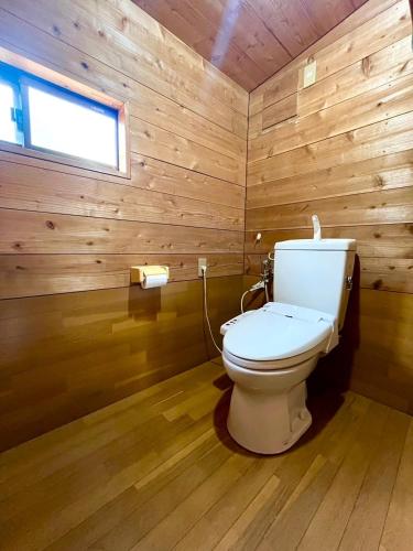a bathroom with a toilet in a wooden wall at ペンションとみや 1組限定 in Oshima