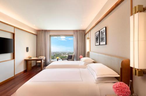 a hotel room with four beds and a large window at Taj City Centre, Patna in Patna