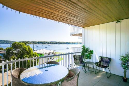 a balcony with a table and chairs and a view of the water at Elegant 2-Bed Apartment with Incredible Bay Views in Batemans Bay