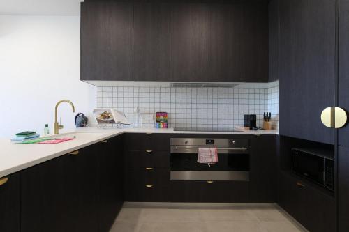 a kitchen with dark brown cabinets and a stove at Elegant 2-Bed Apartment with Incredible Bay Views in Batemans Bay