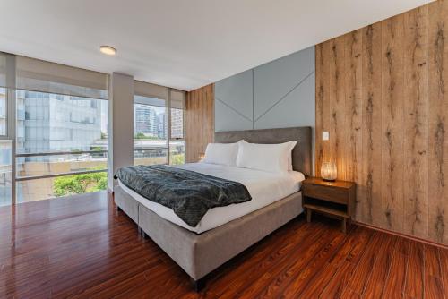 a bedroom with a large bed with a wooden wall at Antara apartments by VH in Mexico City