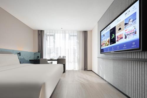 a hotel room with a bed and a flat screen tv at Atour Light Hotel Dongguan Songshan Lake University Town in Dongguan
