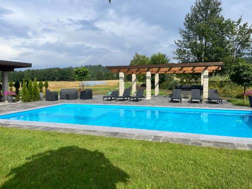 a swimming pool in a yard with a pergola at Sarnia Polana in Kostrzyca
