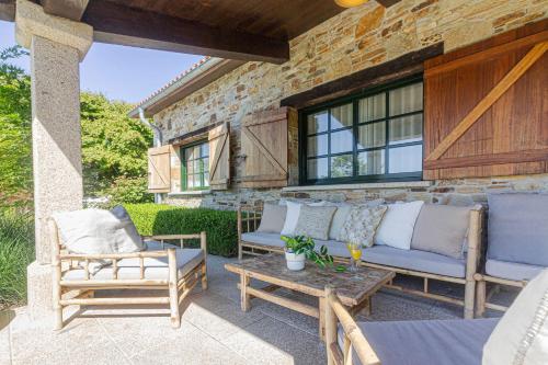 a patio with a couch and two chairs and a table at Elysian Villa in Miño