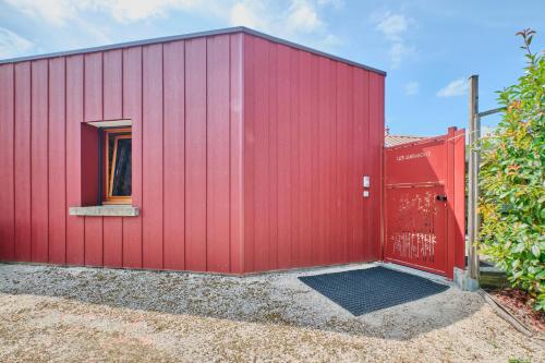 a red shed with a red door and a window at Gîte Les Bambous in Saint-Antoine