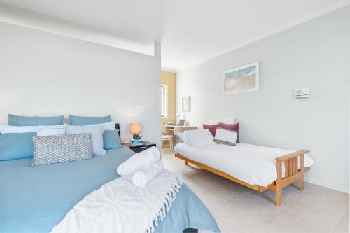 a bedroom with two beds and a table in it at Spyglass Mollymook in Mollymook