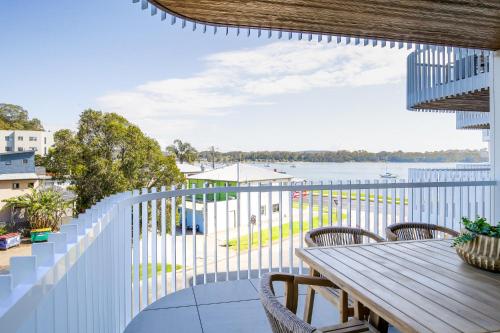 a balcony with a table and chairs and a view of the water at Elegant 2-Bed Apartment with Stunning Views in Batemans Bay