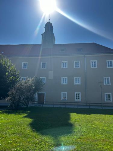 a large white building with the sun shining on it at Schloss Apartment Lankowitz in Maria Lankowitz