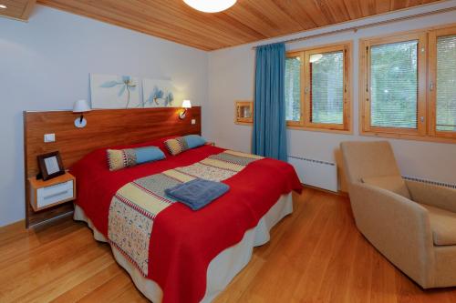 a bedroom with a bed with a red blanket and a chair at KätkänKiisa in Kittilä