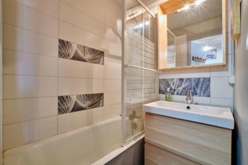 une salle de bain avec un lavabo, une baignoire et un miroir dans l'établissement La montagne, à Les Deux Alpes