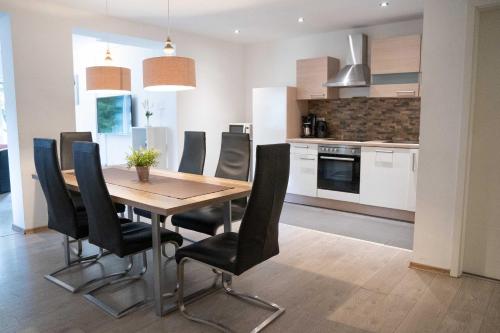 Una cocina y un comedor con mesa y sillas de madera. en Villa Nordhang - Apartment 4, en Winterberg
