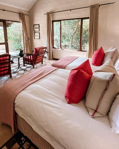 a bedroom with a large bed with red pillows at Fugitives Drift Guest House in Rorkeʼs Drift