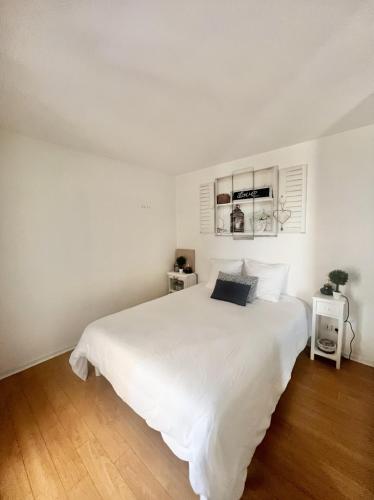 a white bedroom with a large white bed at La PASSERELLE in Toulouse