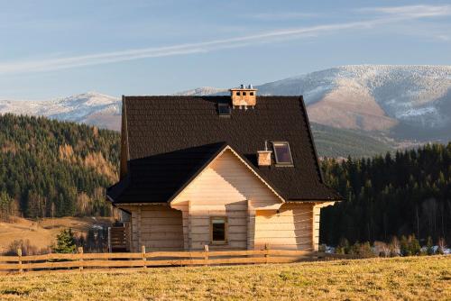 a small house in a field with mountains in the background at Domek na Zawojskim Przysłopiu in Zawoja