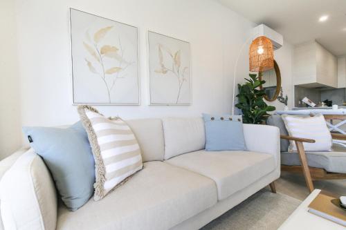 a living room with a white couch with pillows at Bay View 2-Bedroom Apartment with BBQ in Batemans Bay
