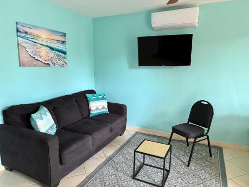 a living room with a black couch and a chair at Coco Cabana Ground Floor Condo in Coco