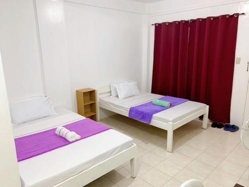 two beds in a room with a red curtain at La Pearla Place Boracay Dmall in Boracay