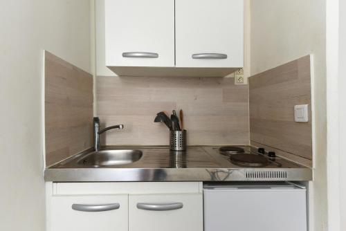 une petite cuisine avec un évier et une cuisinière dans l'établissement Studio Garrigue, à La Fare-les-Oliviers