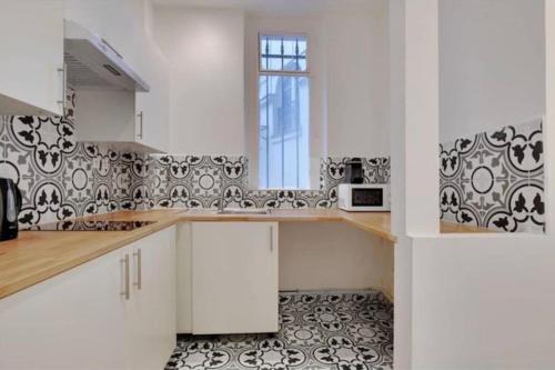 une cuisine avec des armoires blanches et du carrelage noir et blanc dans l'établissement Appartement magnifique paris 18, à Paris