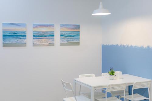 a white dining room with a white table and chairs at Trisisters Home, near Leegarden in Hat Yai