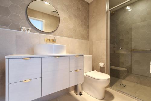 a bathroom with a sink and a toilet and a mirror at Oceanside Apartment with Bay Views in Batemans Bay