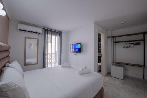 a white bedroom with a large bed and a tv at Hotel Elite Sarande in Sarandë