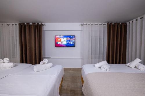 two beds in a room with a tv on the wall at Hotel Elite Sarande in Sarandë