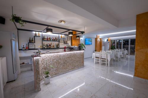 a restaurant with a bar with white tables and chairs at Hotel Elite Sarande in Sarandë