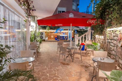a patio with tables and chairs and a red umbrella at Hotel Elite Sarande in Sarandë
