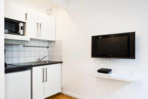 Il comprend une cuisine avec un évier et une télévision murale. dans l'établissement Bluestay 274 - Charmant Appartement à Paris, à Paris