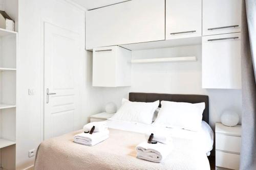 une chambre blanche avec un lit avec deux serviettes dessus dans l'établissement Bluestay 274 - Charmant Appartement à Paris, à Paris
