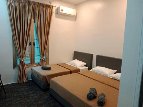 a hotel room with two beds and a window at Nafeeza Roomstay in Jertih