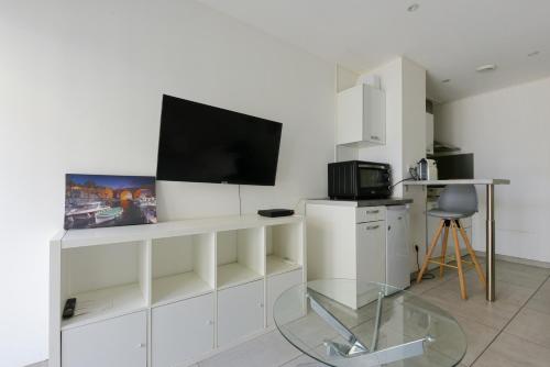 un salon avec une télévision sur un mur blanc dans l'établissement Provençal Studio Netflix Appart-hotel-Provence, à La Fare-les-Oliviers