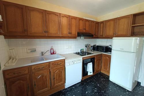 une cuisine avec des armoires en bois et un réfrigérateur blanc dans l'établissement 75m apartment in Saint-Jean-de-Maurienne, à Saint-Jean-de-Maurienne