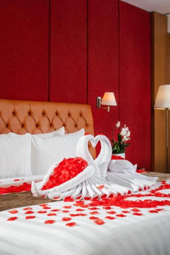 a bed with two swans and red roses on it at Merapi Merbabu Hotel Yogyakarta Powered by Archipelago in Yogyakarta