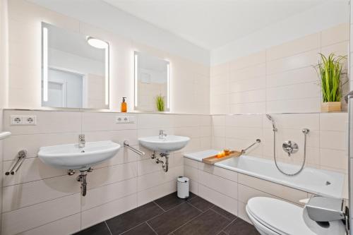 ein weißes Badezimmer mit 2 Waschbecken und einer Badewanne in der Unterkunft Heimathafen mit See- & Bergsicht in Friedrichshafen