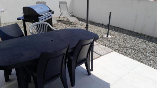a black table with chairs and a grill on a patio at Logement 5 mn de la mer Milla 2 in Ventiseri