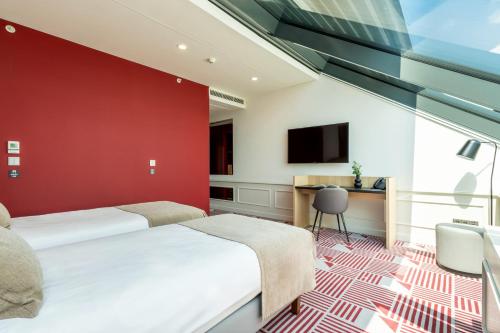 two beds in a room with a red wall at Hotel Oktogon Haggenmacher by Continental Group in Budapest