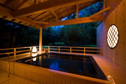 a hot tub on a wooden deck with a wooden ceiling at Sennomori in Ise